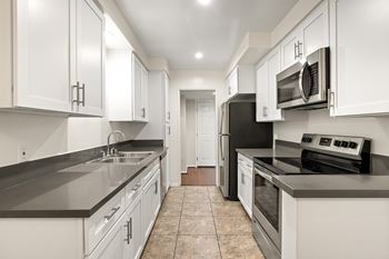 A kitchen with white cabinets and black appliances. at White Oak Terrace Apartments, Encino, CA